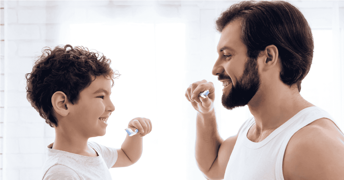 Shutterstock 1086710552 01 Man and boy both holding toothbrushes in front of mouths
