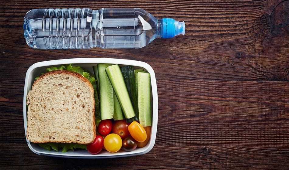 School Lunch For Children With Braces Water bottle and container with sandwich and fresh vegetables